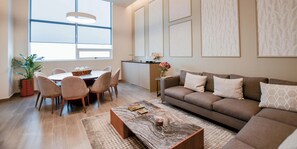 Una sala de estar moderna con sofá, mesa de centro, mesa de comedor, sillas y una planta en maceta.