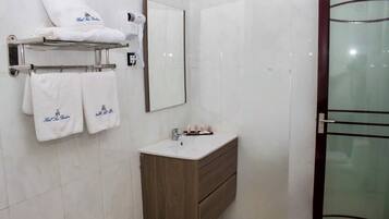 A bathroom with a mirror, a sink, a towel rack with towels, and a glass shower door.