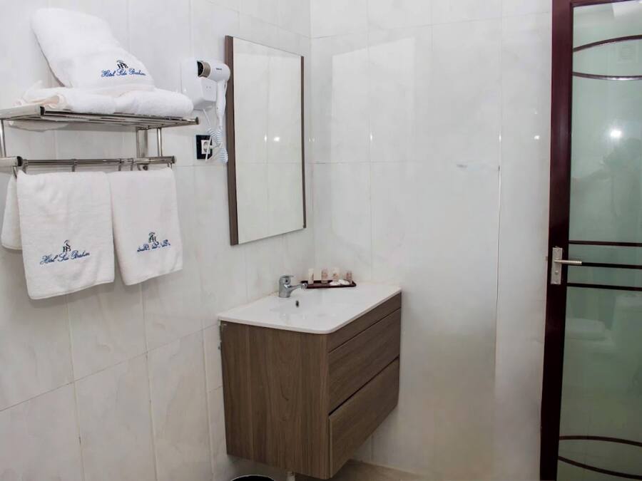 A bathroom with a mirror, a sink, a towel rack with towels, and a glass shower door.