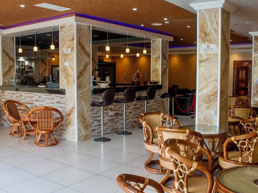 Eine Hotelhalle mit Korbsesseln, einer Bar und Marmorsäulen.