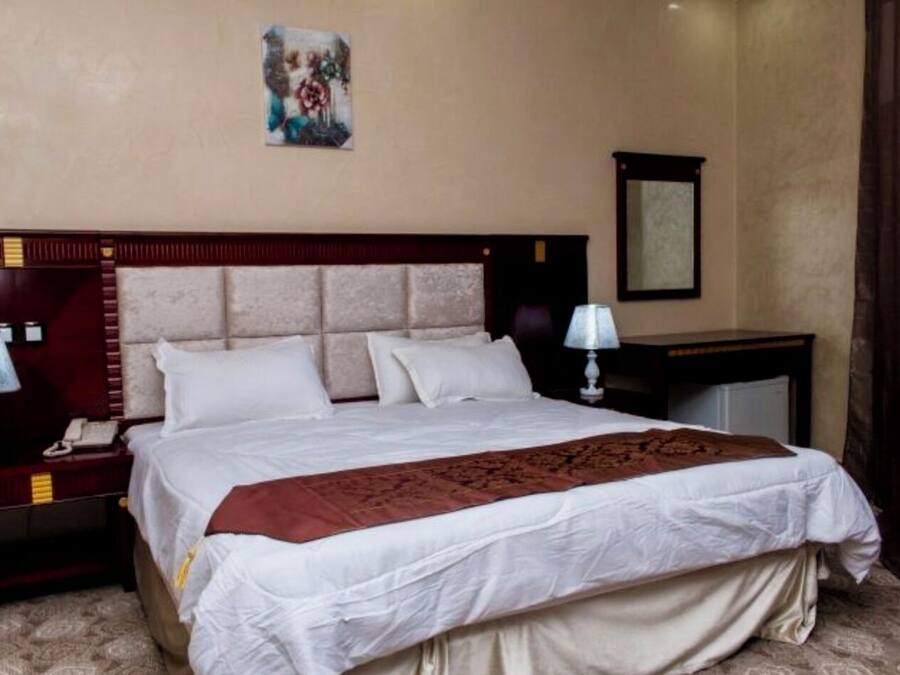 Una habitación de hotel con una cama grande, dos mesitas de noche, una escrivanía y una silla.