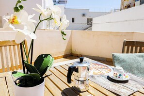 A table with a coffee maker, a cup, and a plate with food, alongside a potted plant and white flowers. - Respiro del Mare by Casa di Marco (Conchiglie-Alto Lido)