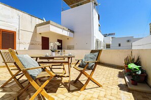 Un patio exterior con una mesa, sillas y plantas en macetas.