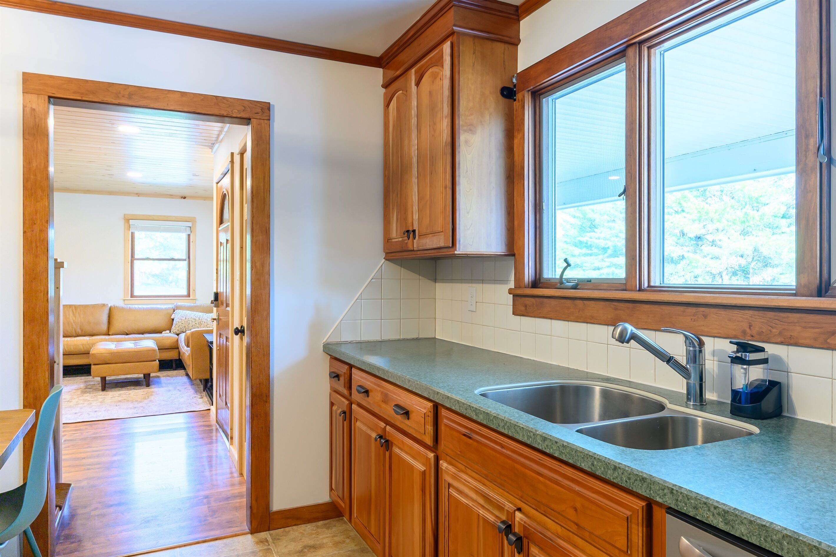 A kitchen with wooden cabinets, a double sink, and a window.