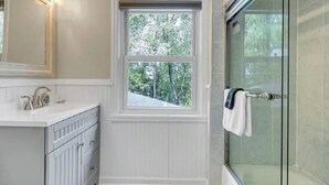 Un bagno con finestra, doccia e mobile toilette con specchio.
