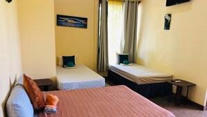A bedroom with a large bed, two smaller beds, a desk, and a painting on the wall.