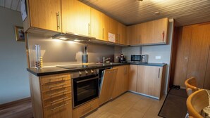 Eine moderne Küche mit Holzschränken, einer Edelstahl-Dunstesse, einem Einbauofen und einer Mikrowelle.