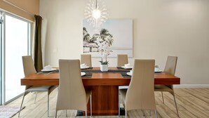 A dining area with a wooden table, six chairs, a chandelier, and a painting on the wall. - Private Pool 4BR Getaway in ChampionsGate (Four corners)