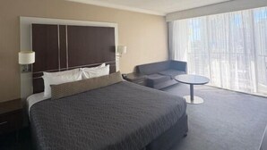 A hotel room with a large bed, a sofa, a small table, and a large window with curtains. - View - 1627 (1BR/1BA) (Gold Coast)