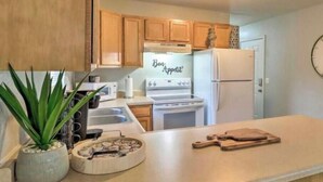 A kitchen with wooden cabinets, a stove, a refrigerator, a sink, and a clock on the wall. - West Plains 2BR Near Downtown Pet Friendly Stay (West Plains)