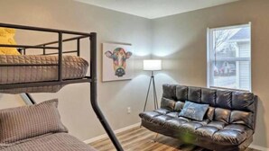 A room with a bunk bed, a leather sofa, a lamp, and a window with blinds. - West Plains 2BR Near Downtown Pet Friendly Stay (West Plains)