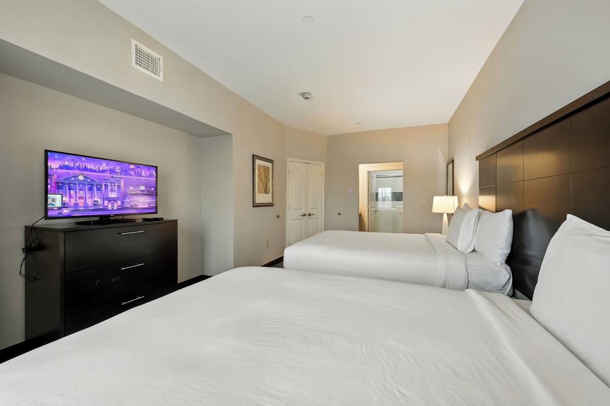 Une chambre d’hôtel avec deux lits, une télévision, une commode et une porte.