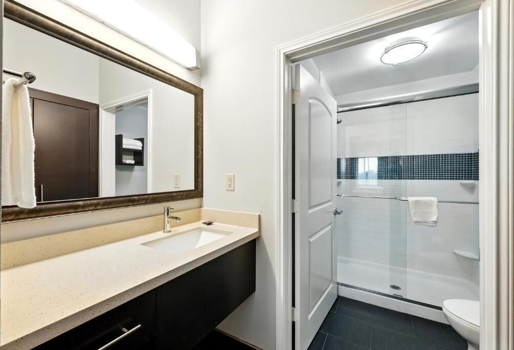 A bathroom with a sink, mirror, and shower.