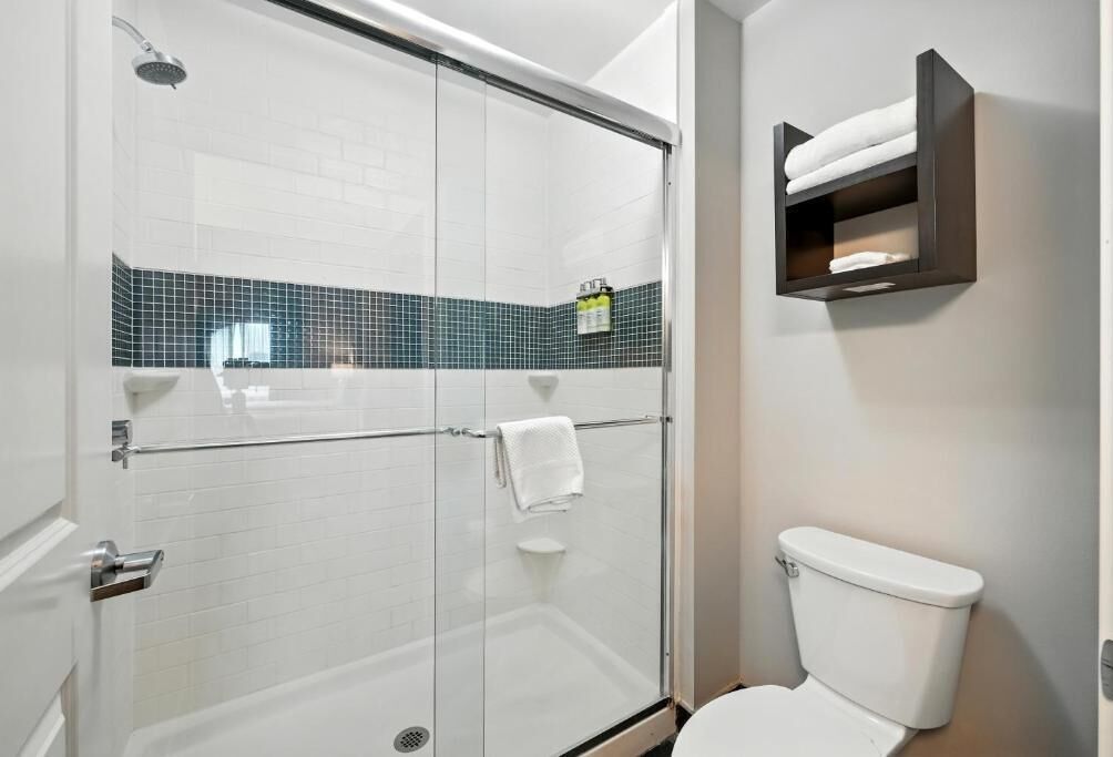 Ein Badezimmer mit Duschkabine, weißer Toilette und Handtuchhalter mit Handtüchern.