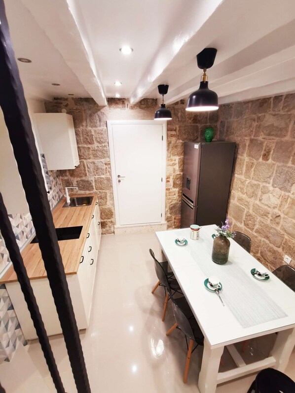 A modern kitchen with a white countertop, stone wall, and a door leading to another room.