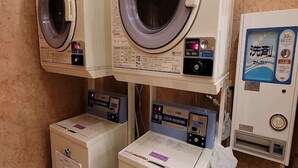 Une laverie équipée de plusieurs machines à laver et d’un distributeur de lessive.