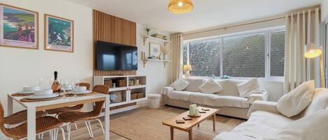 A modern living room with a dining area, a television, and a large window.