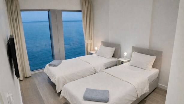 A hotel room with two beds, a TV, and a view of the sea. - ✨ River View Apartment Near O2 | Sleeps 6 | Prime Location London ✨ (london)