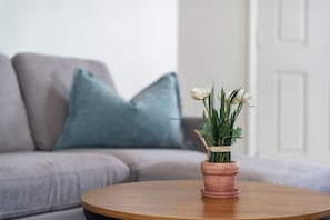 Ein runder Holztisch mit einem Terrakottatopf, der weiße Blumen und grünes Laub enthält.