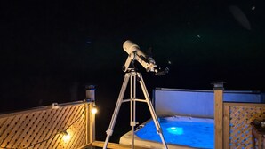 A telescope on a tripod on a wooden deck with a hot tub in the background. - 51 Acre Summer Farmhouse-Hottub, Stargazing, BBQ-Sleeps upto 8 (Colborne)