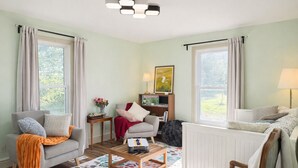A cozy living room with a sofa, armchair, coffee table, and a bookshelf. - 51 Acre Summer Farmhouse-Hottub, Stargazing, BBQ-Sleeps upto 8 (Colborne)