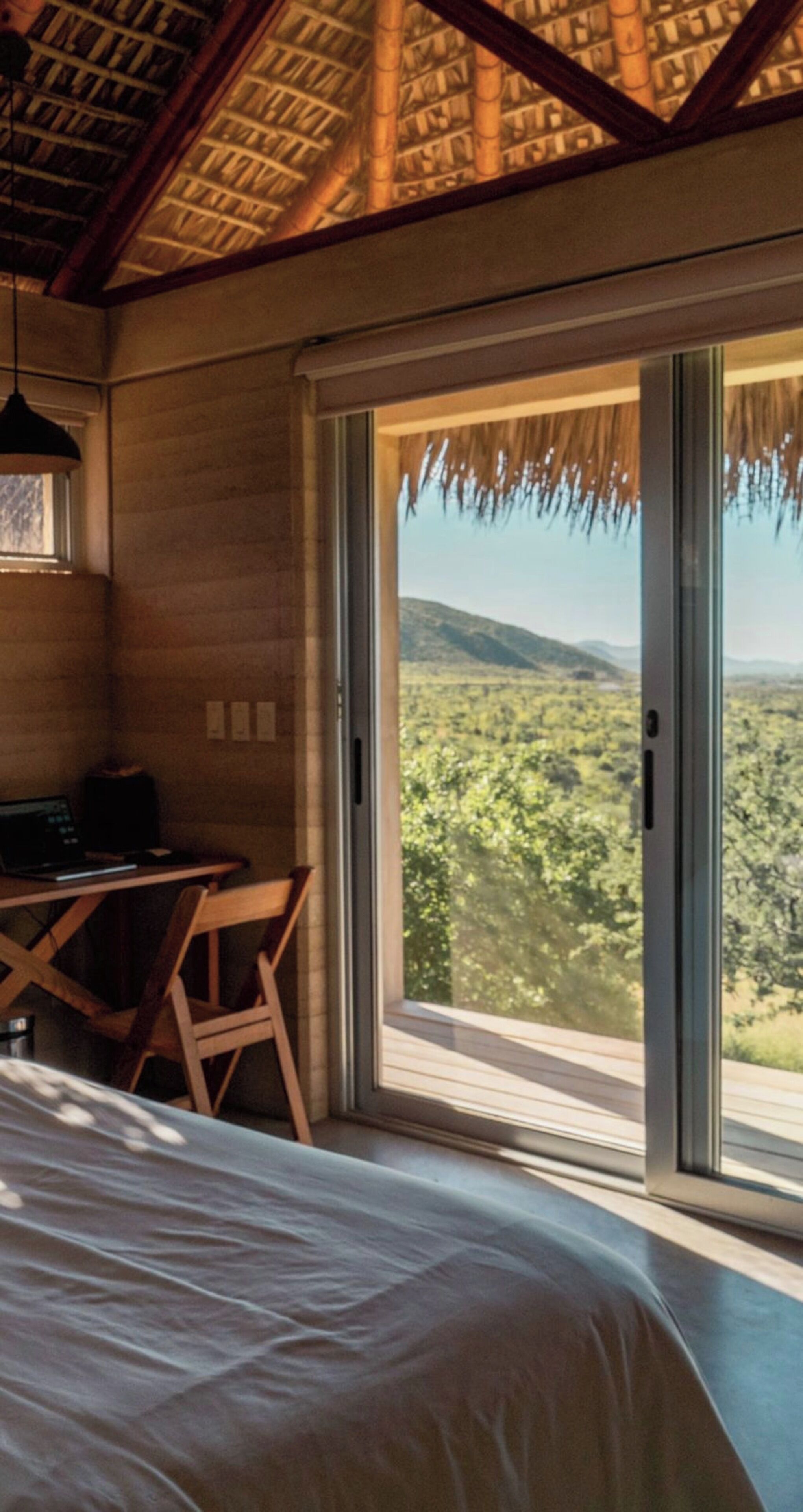 Un dormitorio con una cama grande, un escritorio y vistas a un paisaje montañoso a través de un ventanal corredero.