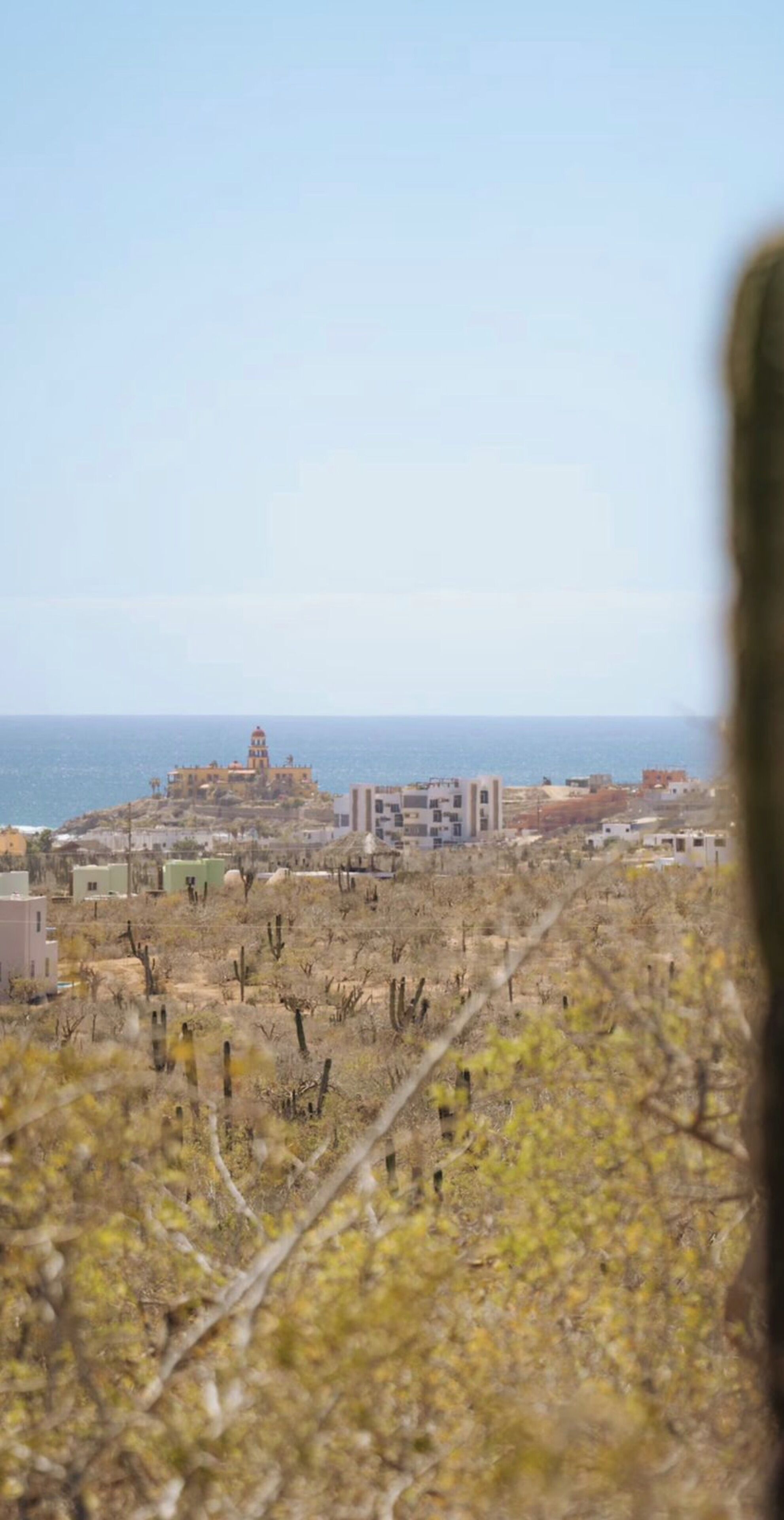 Une ville côtière avec des bâtiments, un phare et un paysage aride.