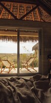 Una habitación con un amplio ventanal corredera que da a una terraza exterior con dos sillas de madera.