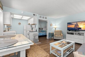 A compact living space with a kitchenette, a dining area, a seating area with a TV, and a bed with a patterned headboard. - (Saint Pete Beach)