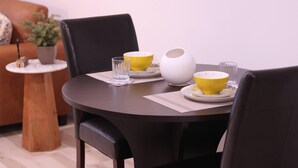 A dining table with chairs, a potted plant, and a small side table with a bowl and a glass.