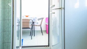 A kitchen with a refrigerator, a dining table with chairs, and a glass door leading to an outdoor area with a chair and a trash bin. - Apartment 2425/200961 (Istria - Rovinj), 1300m from the beach (Rovinj)