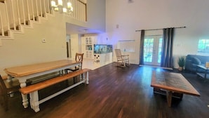 Uma sala de estar ampla com um banco de madeira, uma escada, um aquário e vista para o exterior.