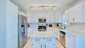 A modern kitchen with white cabinets, stainless steel appliances, and a central island. - 3-bedroom gem in Central Phoenix (Phoenix)