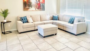 A living room with a sectional sofa, a coffee table, a painting, a ceiling fan, and a window with blinds. - 3-bedroom gem in Central Phoenix (Phoenix)