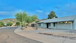A residential street with a house featuring a garage, a small garden, and a hilly backdrop. - 3-bedroom gem in Central Phoenix (Phoenix)