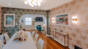 Un comedor con una mesa larga, sillas, una chimenea blanca y un televisor.