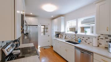 Una cocina moderna con alacenas blancas, un refrigerador de acero inoxidable, un lavavajillas y un ventanal con vistas.