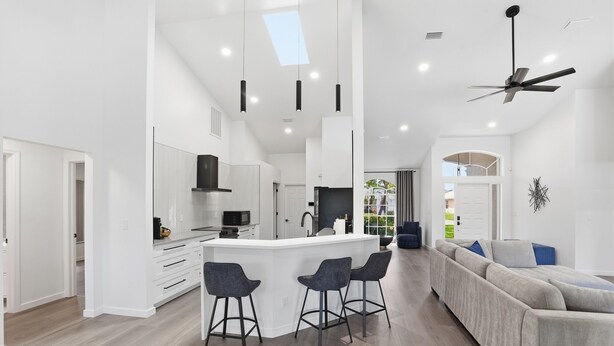 A modern kitchen with a central island, bar stools, and a ceiling fan. - 2026 Renovated Luxury Home. Heated Pool. 10 mins to 5th Ave, Pier Beach (Naples)