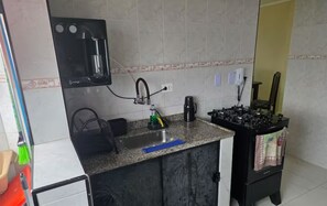 A kitchen with a sink, stove, and various kitchen items. - Beachfront apartment (Praia Grande)