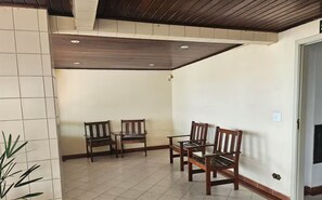 Une pièce avec un sol carrelé, un plafond en bois et deux chaises en bois.