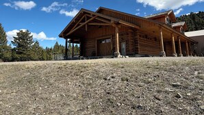 A wooden cabin with a porch, large windows, and a stone foundation. - Beautiful 3-bedroom barn apartment right next to Yellowstone National Park (Gardiner)