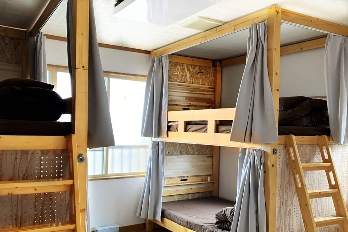 Habitación con literas, una escalera, ventana y pared de madera.