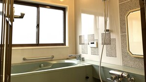 Ein Badezimmer mit Badewanne, Dusche, einem Fenster und einem Handtuchhalter.