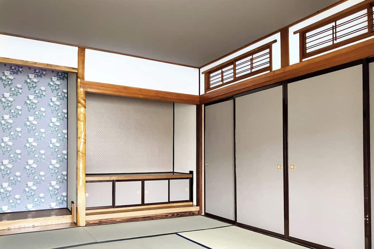 Una habitación tradicional japonesa con suelo de tatami, puertas correderas y techo de madera.