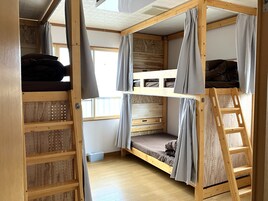 Habitación con literas, una escalera, estantes de madera y una ventana.