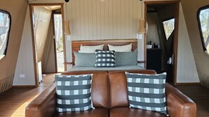 A cozy bedroom with a bed, a brown leather sofa, and a wooden table.