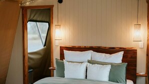 A cozy bedroom with a wooden headboard, a bed with white and green bedding, and two wall-mounted lamps.