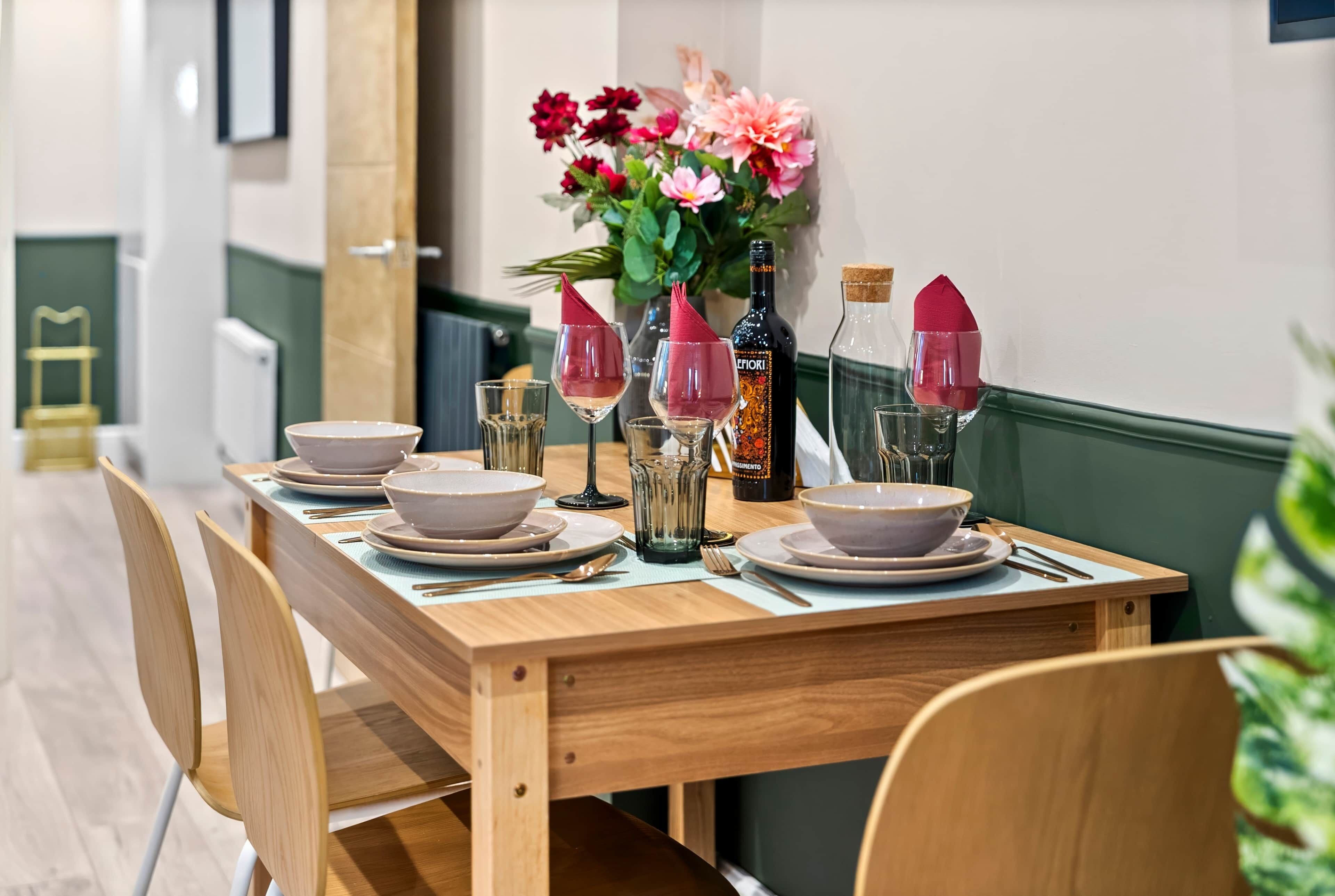 A dining table set with bowls, glasses, and a bottle, surrounded by chairs.