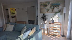Un salon avec un canapé, une carte du monde accrochée au mur, une plante en pot et un lampadaire.