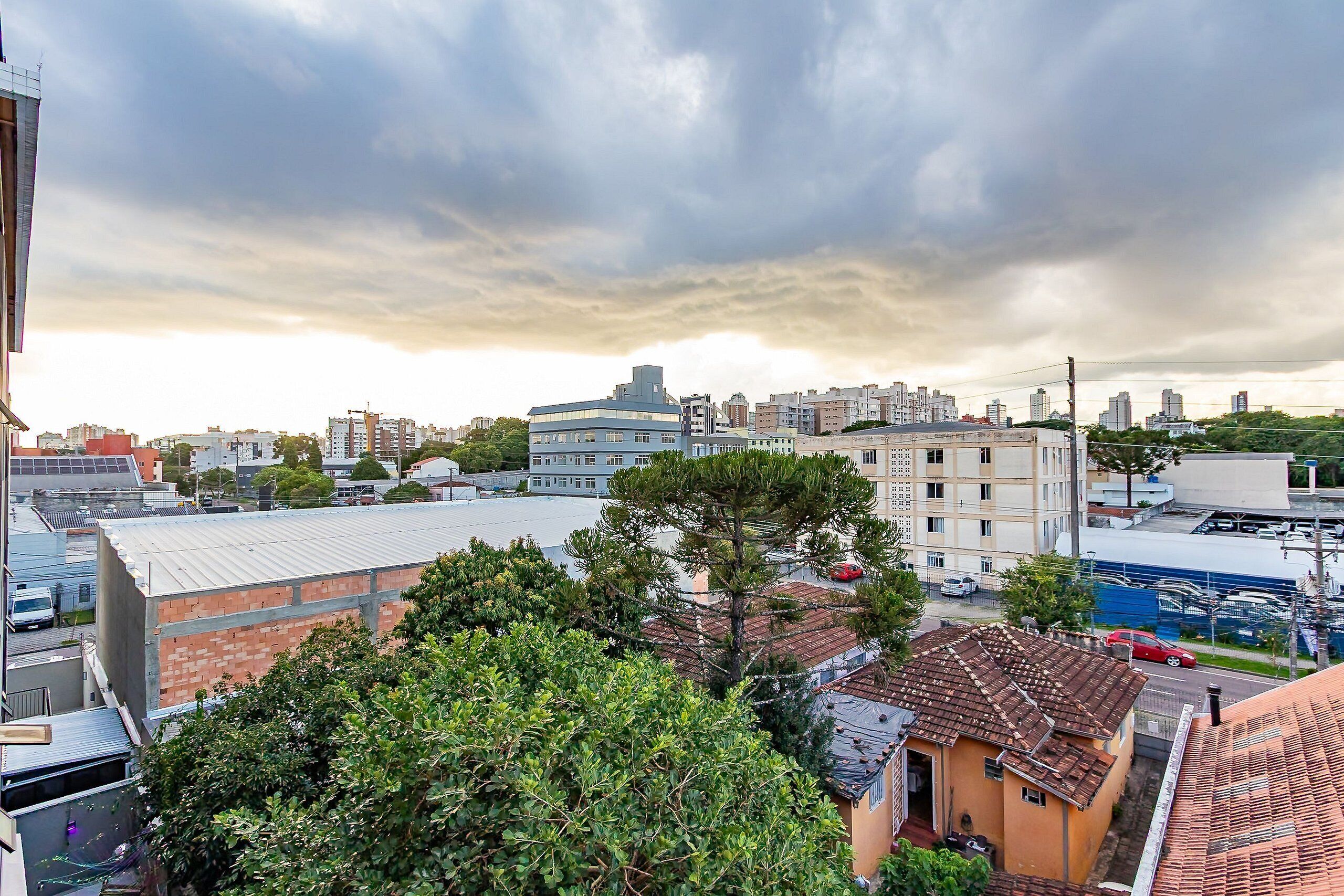Paesaggio urbano con edifici, alberi e cielo nuvoloso.